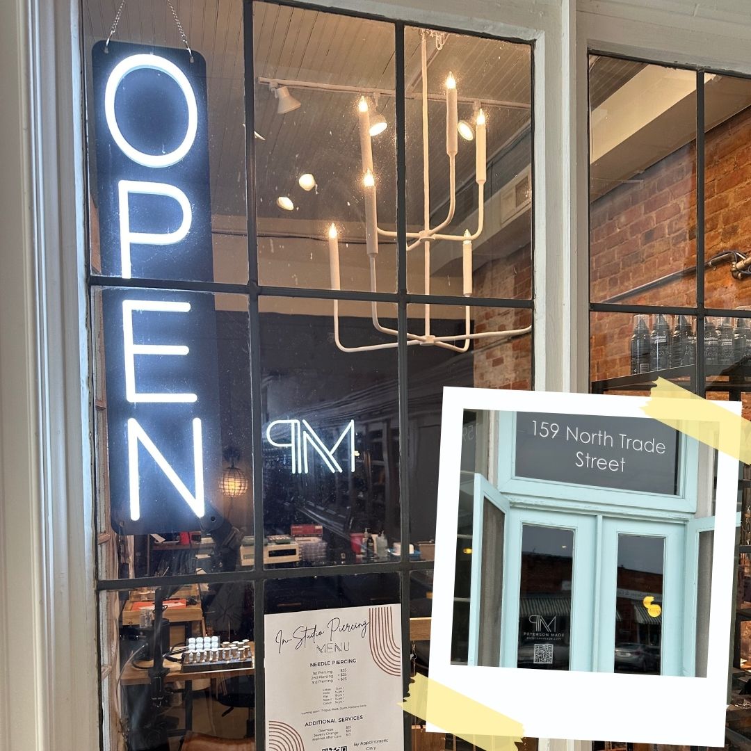 Peterson MADE Neon 'OPEN' sign on a glass door with a reflection of interior decor. Peterson MADE at Moxie Mercantile