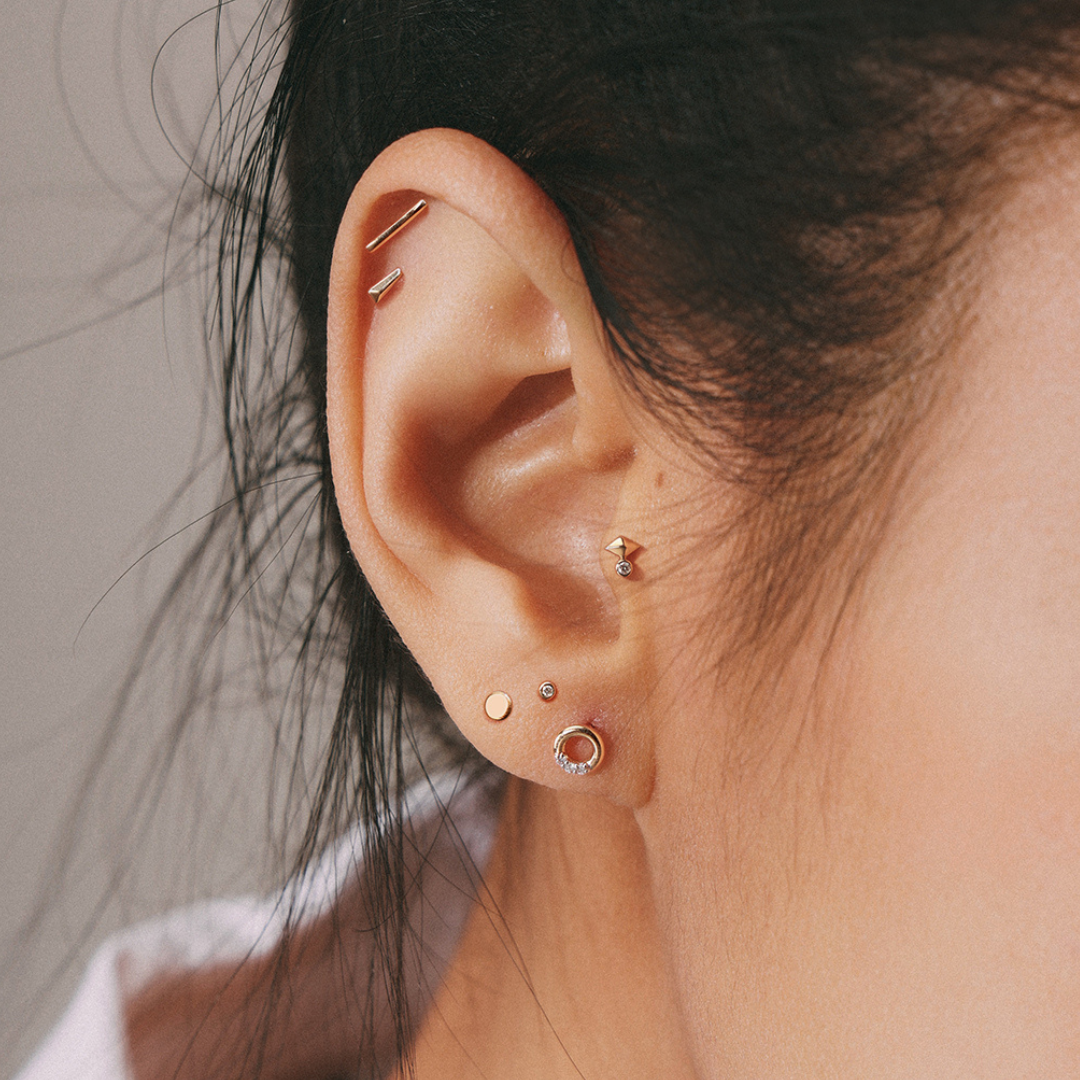 14k Gold Flat Disc showed on a women's earlobe, along with other gold earrings. 